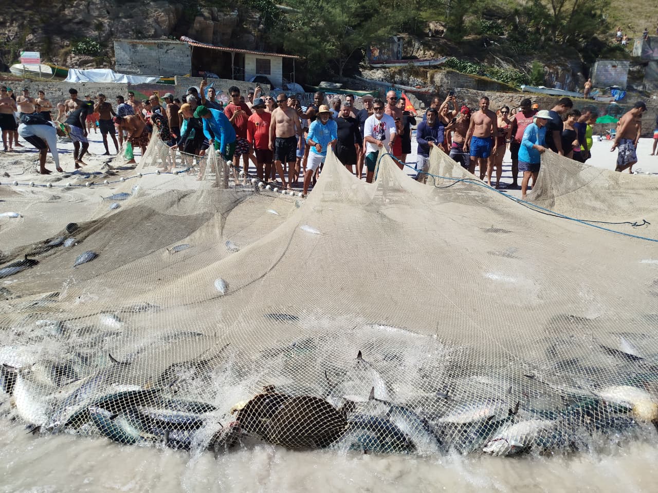 Comunidade reunida com redes de pesca na praia