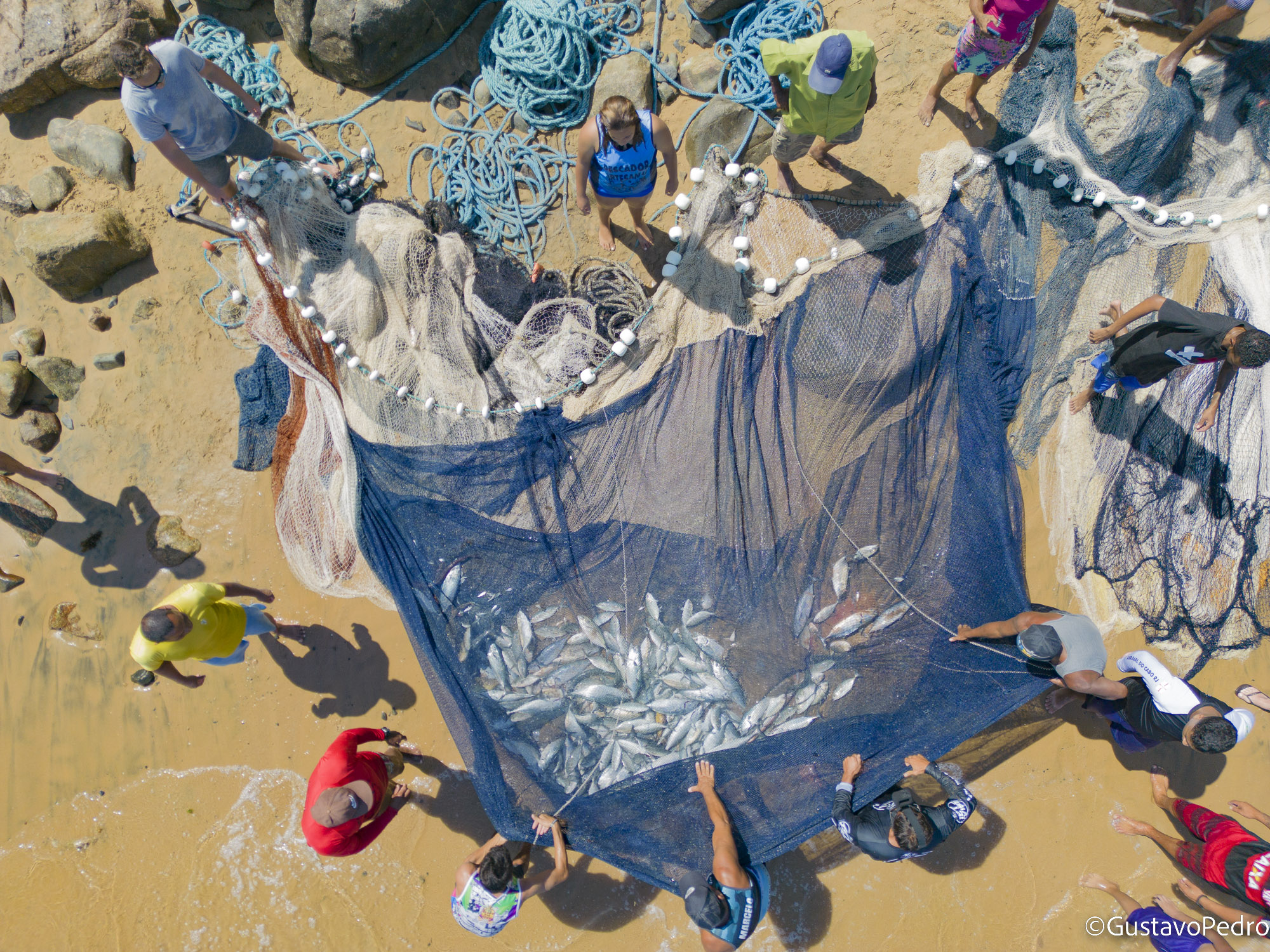 Pessoas trabalhando juntas com redes de pesca na praia