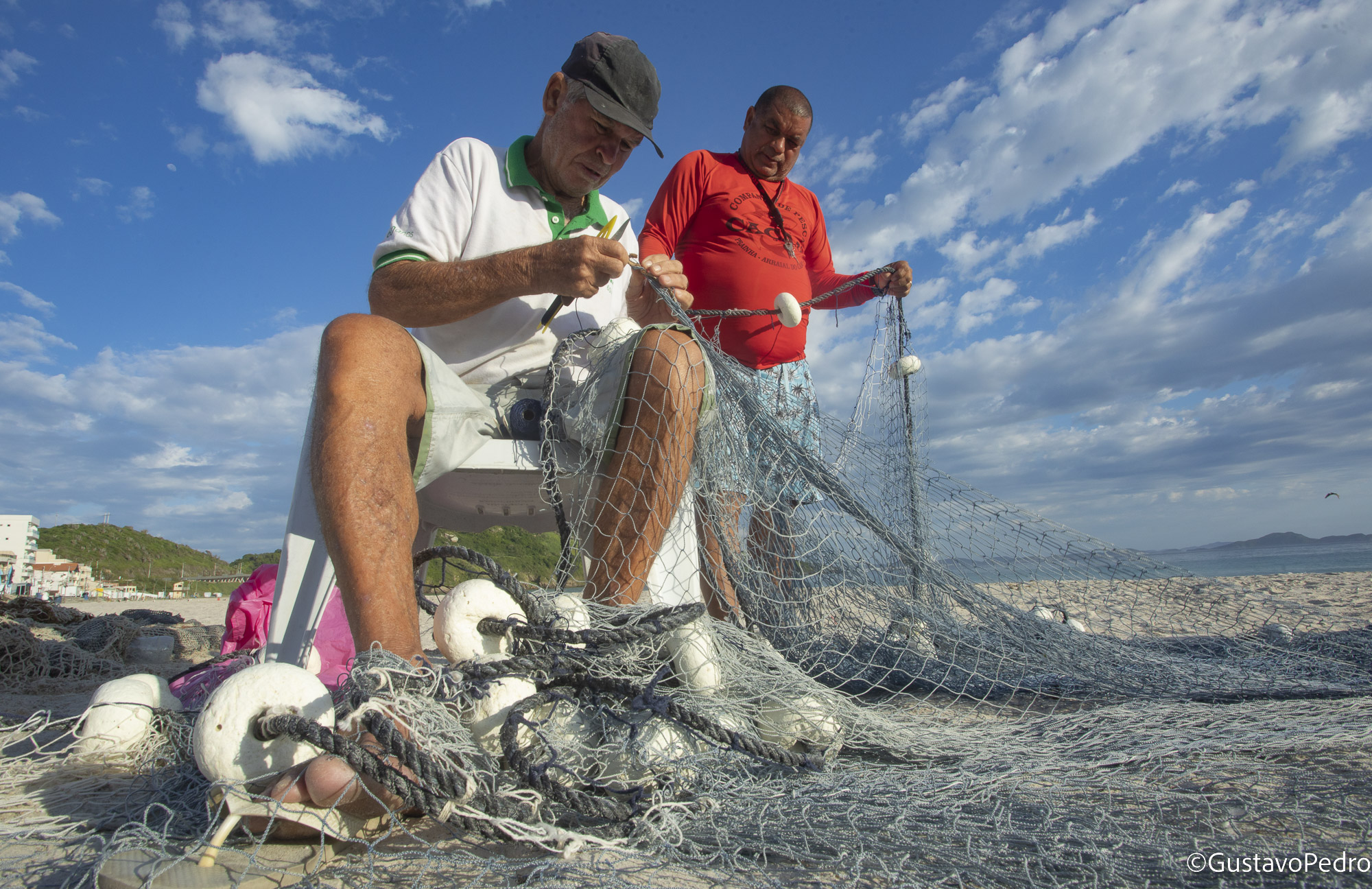 Dois pescadores trabalham juntos com uma rede na praia